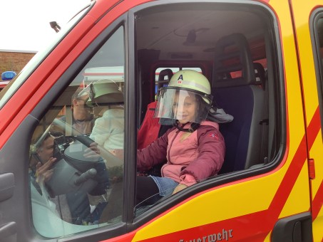 Ein Kind sitzt im Feuerwehrauto